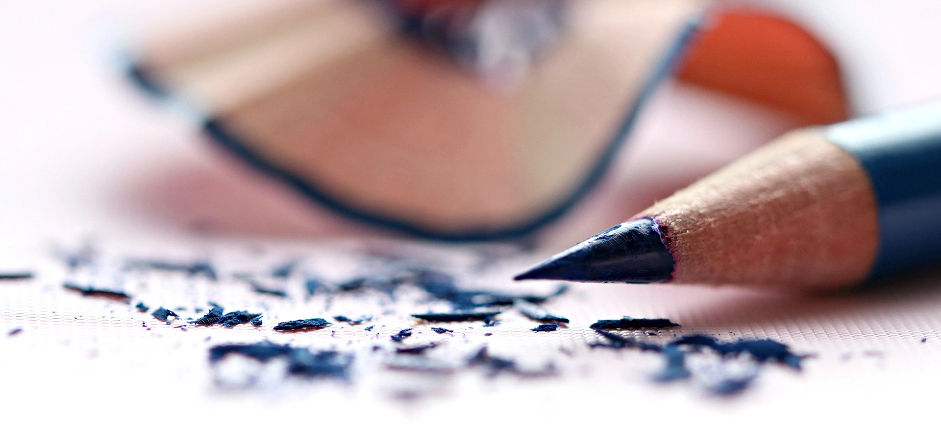 Imatge de fons d'una maquineta i un llapis al que s'acaba de fer-li punta.